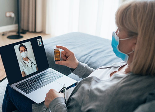 woman on a telehealth call with a Hammond-Henry Hospital physician while checking directions on medication bottle